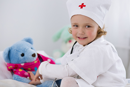 Cute little girl dressed as doctor playing with toy