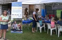 DSCC tent at state fair shows vertical banner with children coloring in the background