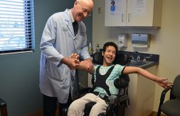 Dr. Keith Gabriel smiles as he holds patient, Bayan's hand