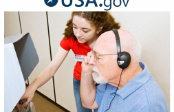 Elections worker assists man wearing headphones at voting booth