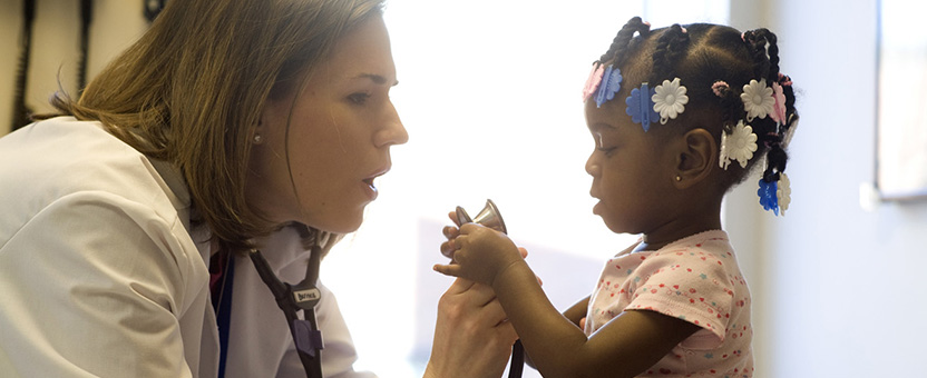Doctor holds stethoscope in front of young girl
