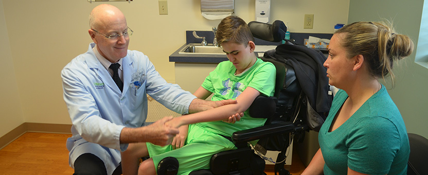 Pediatric orthopedic surgeon checks the arm of a DSCC participant during an orthopedic clinic