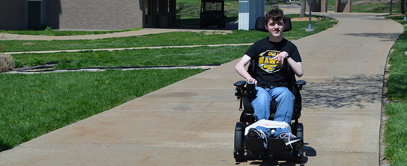 DSCC participant Jacob Flynn traveling in his wheelchair on the Quincy University campus