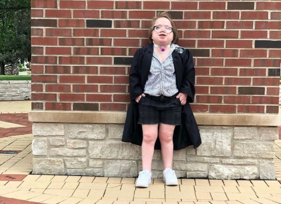 Makenzie Hardesty smiles while wearing her high school graduation gown