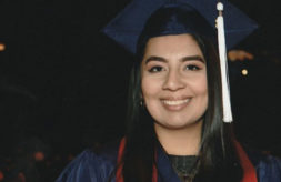 DSCC former participant and current employee Lisette Rios smiles while wearing her graduation cap and gown.