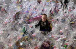 Axel Johnson smiles as he sits surrounded by hundred of wrapped Easter basket donations