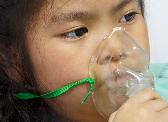 Young girl holding an oxygen mask up to her face